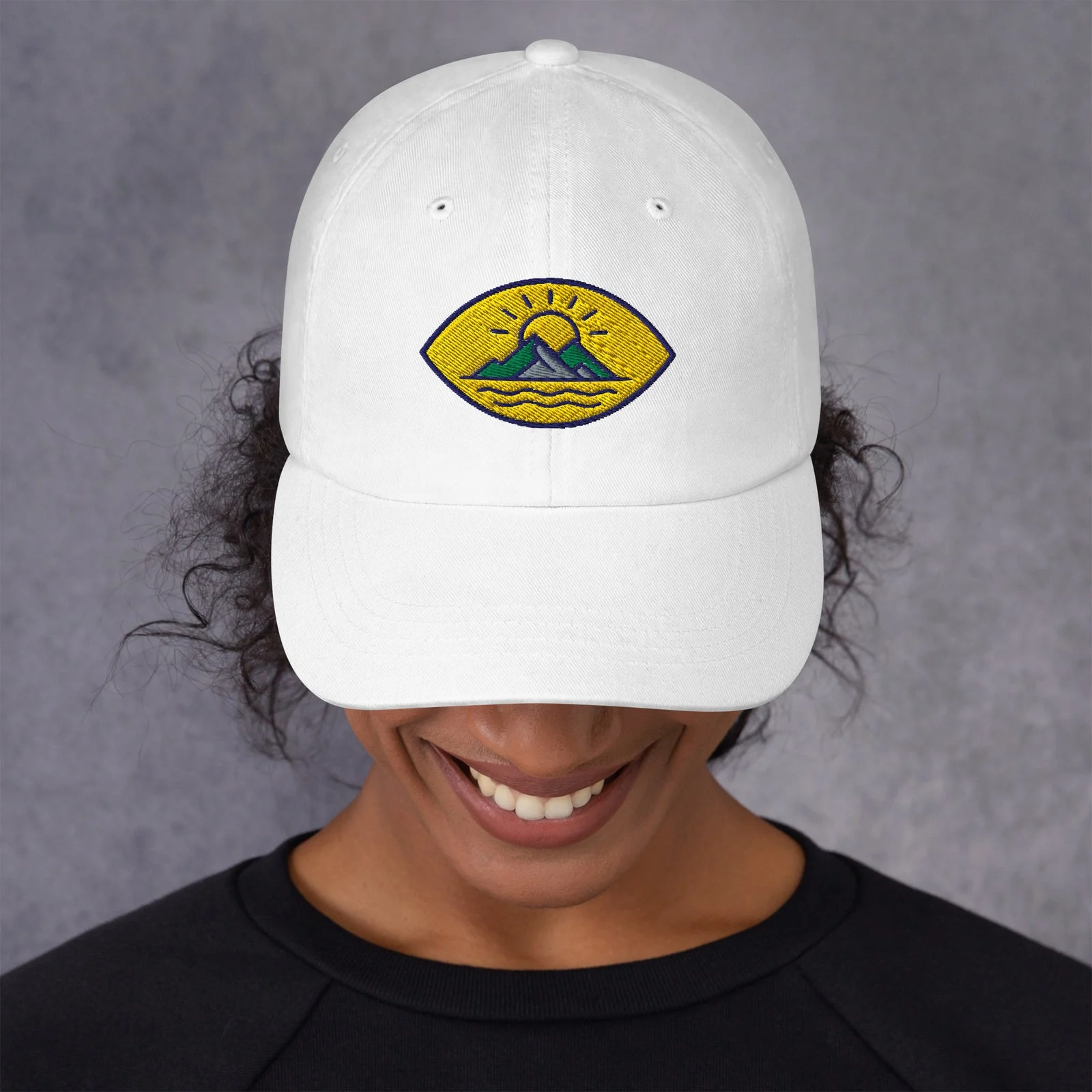 Chica con la gorra dad hat blanca y un parche bordado de montañas y sol