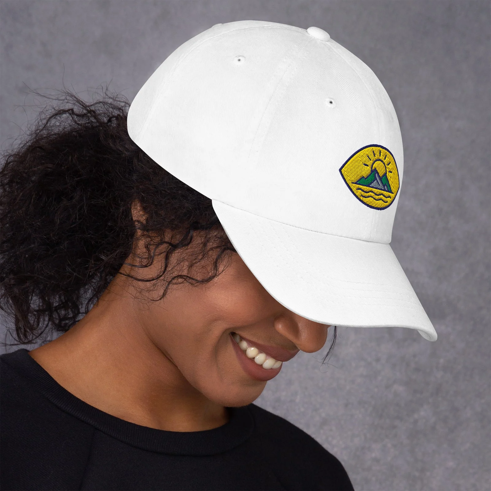 Chica sonriendo con la gorra dad hat blanca, perfil